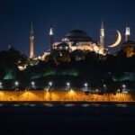 A stunning nighttime view of Hagia Sophia Grand Mosque in Istanbul with a crescent moon in the backdrop.