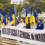 Group of people protesting against Russian actions in Ukraine with Ukrainian flags in Portugal.