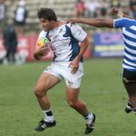 Rugby players in motion during a competitive game on a grassy field.